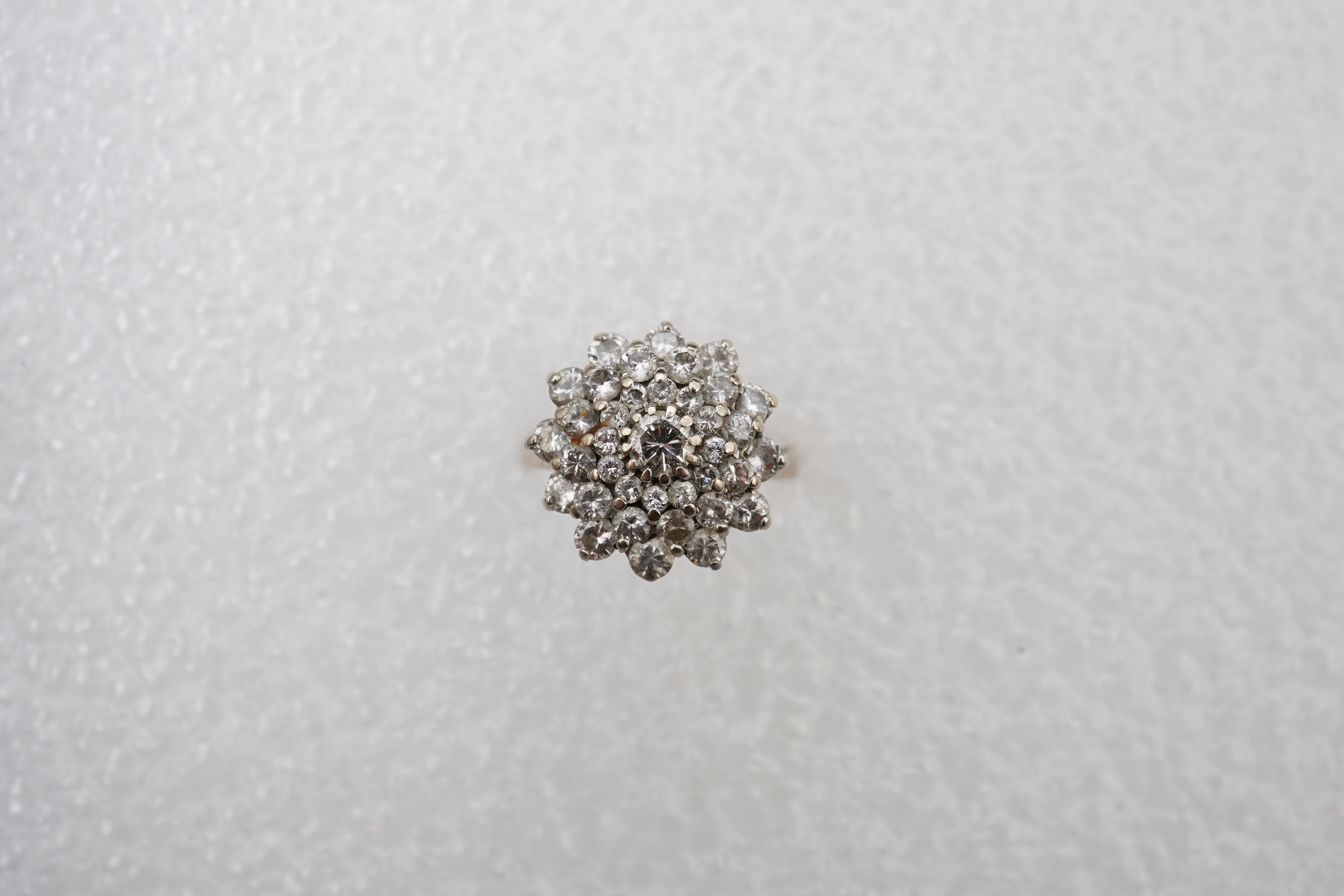 A white gold and diamond cluster ring, set with a concentric arrangement of brilliant-cut diamonds totalling approximately 1.50 carats, size M, gross weight approximately 5 grams